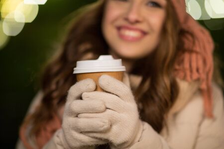 happy woman with coffee over christmas lightsの写真素材