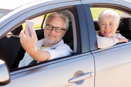 senior couple in car taking smartphone selfieの写真素材