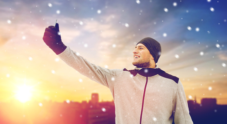 man taking selfie with smartphone in winterの写真素材