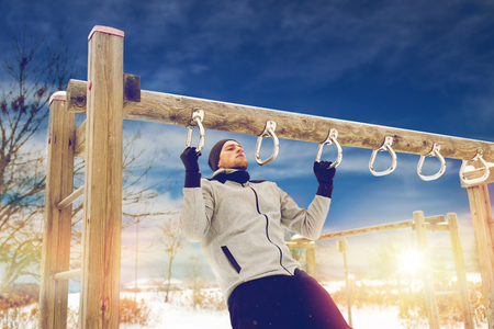 young man exercising on horizontal bar in winter
