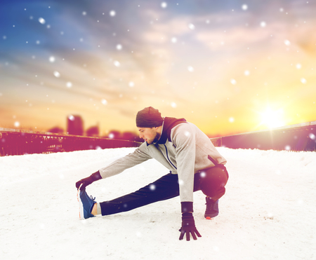 man exercising and stretching leg on winter bridgeの写真素材