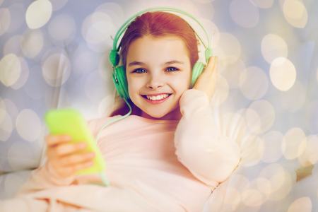 girl with headphones listening to music in bedの写真素材