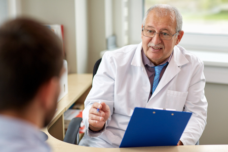 senior doctor talking to male patient at hospitalの写真素材