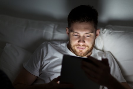 young man with tablet pc in bed at home bedroom