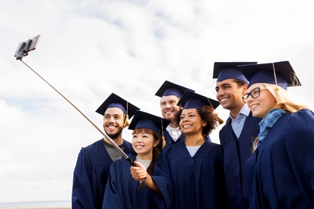 group of happy students or graduates taking selfieの写真素材