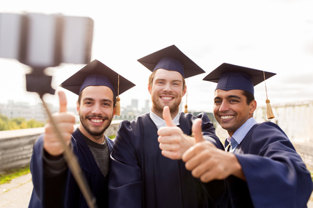happy male students or graduates taking selfieの写真素材