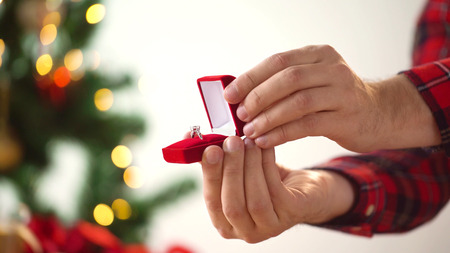 close up of hands with ring in christmas gift box