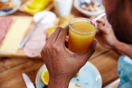 close up of male hand with glass of orange juice