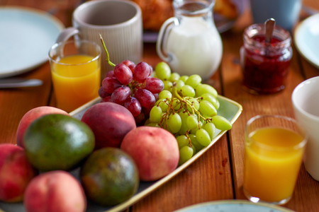 fruits, juice and other food on table at breakfastの写真素材