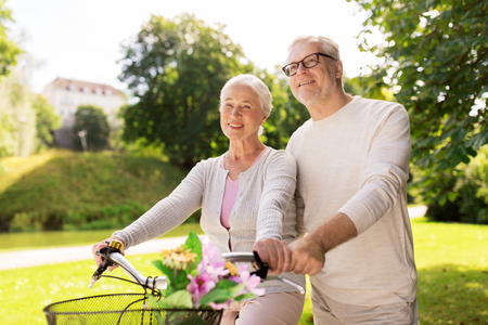 happy senior couple with bicycles at summer parkの写真素材