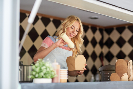 happy saleswoman making wok at food truckの写真素材