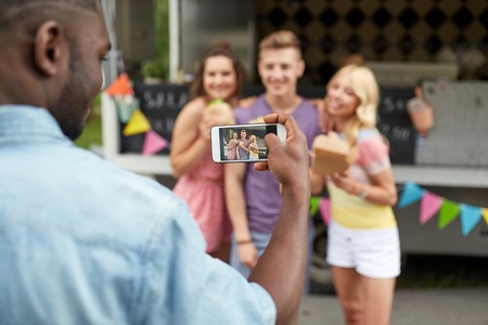 man taking picture of friends eating at food truckの写真素材