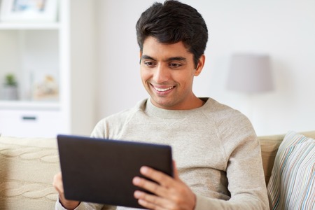 smiling man with tablet pc at homeの写真素材