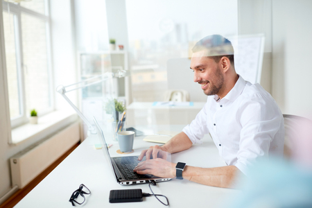 happy businessman typing on laptop at officeの写真素材