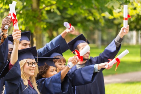 happy students in mortar boards with diplomasの写真素材
