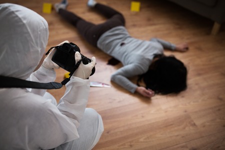 criminalist photographing dead body at crime scene