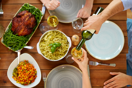 thanksgiving day, eating and leisure concept - group of people having dinner at table with food and drinking wineの写真素材