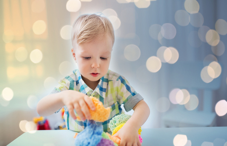childhood, creativity, arts, activity and people concept - happy little baby boy playing with ball clay at homeの写真素材