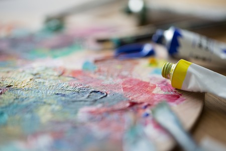 fine art, creativity, painting and artistic tools concept - close up of acrylic color or paint tubes and paletteの写真素材