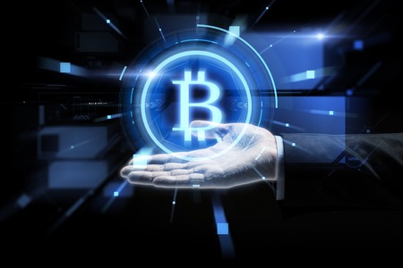 cryptocurrency, finance and business concept - close up of businessman hand with virtual bitcoin symbol hologram over black backgroundの写真素材