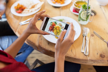 hands with smartphone picturing food at restaurantの写真素材