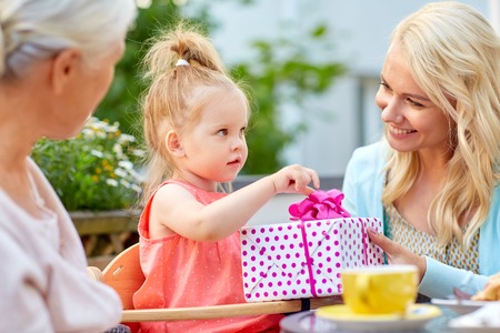 happy mother giving present to daughter at cafe