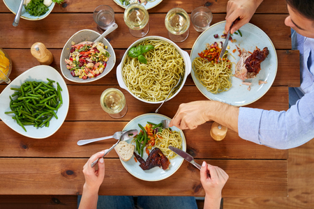 couple at table with food eating pasta and chickenの写真素材