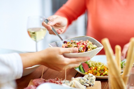 people eating salad at table with foodの写真素材