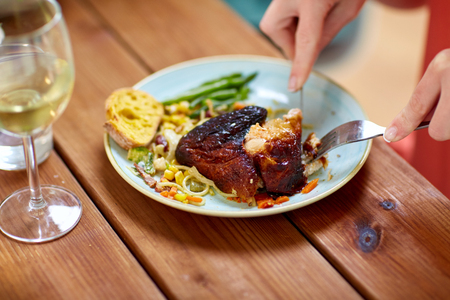 hands of woman with fork eating roast chickenの写真素材