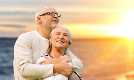 happy senior couple over sunset background