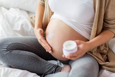 close up of pregnant woman applying cream to bellyの写真素材