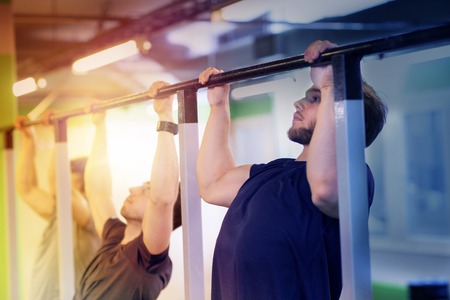 group of young men doing pull-ups in gymの写真素材