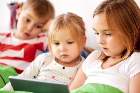 little kids with tablet pc in bed at homeの写真素材