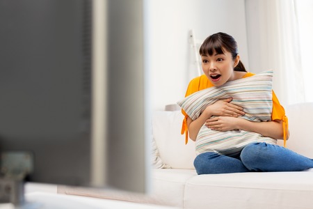 stunned asian woman with watching tv at homeの写真素材