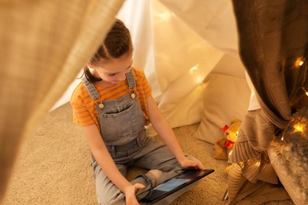little girl with tablet pc in kids tent at homeの写真素材