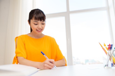 happy student girl with book and notebook at homeの写真素材