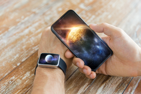 close up of hands with smartphone and smart watchの写真素材