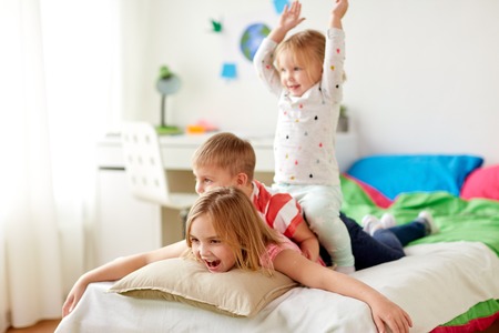 happy little kids having fun in bed at homeの写真素材
