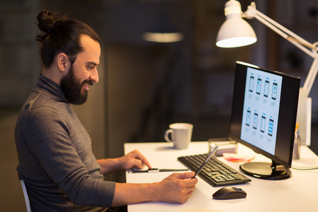 man with smartwatch and tablet pc at night officeの写真素材