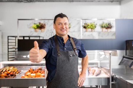 seafood seller at fish shop showing thumbs upの写真素材