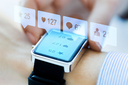 modern technology and people concept - close up of woman hands wearing smart watch with social media iconsの写真素材
