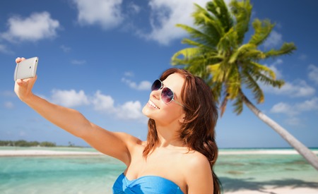 woman taking selfie by smartphone on beachの写真素材