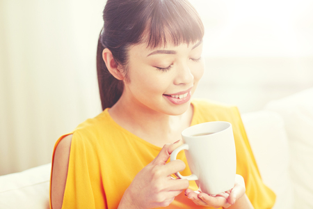 happy asian woman drinking from tea cupの写真素材