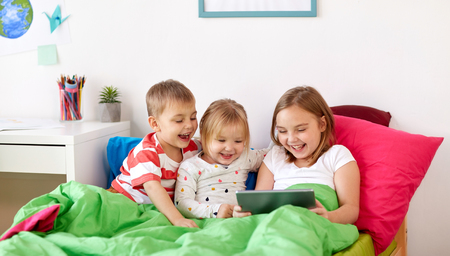 little kids with tablet pc in bed at homeの写真素材