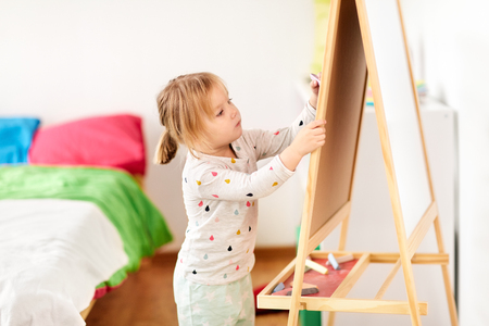 happy little girl drawing on chalk board at homeの写真素材