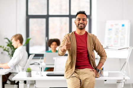 smiling indian man showing thumbs up at officeの写真素材