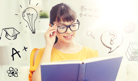smiling young asian woman reading book at homeの写真素材