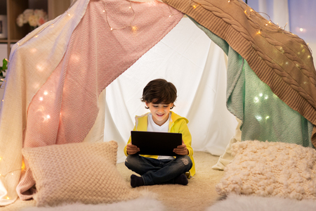 little boy with tablet pc in kids tent at homeの写真素材