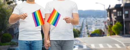 male couple with gay pride flags holding handsの写真素材