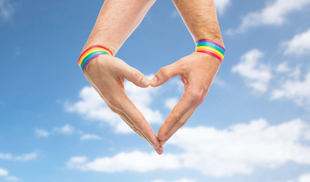 male hands with gay pride wristbands showing heartの写真素材